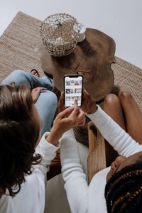 Two individuals sitting together while scrolling on a phone. If you're looking to enhance your social media presence but don't know where to start, contact us! Our social media manager would love to help. 