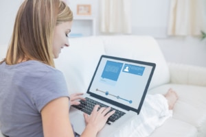 A smiling woman updating an online profile on her laptop, showing how Local SEO for doctors and SEO for doctors are supported by complete, optimized business profiles. Doctor SEO consulting ensures medical professionals appear in local search results where patients are looking. 