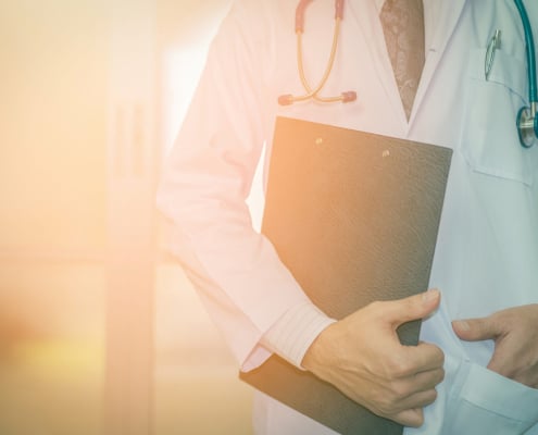 Physician standing with a clipboard and stethoscope. Grow your practice and attract the right patients using seo for functional medicine doctors and expert strategies.