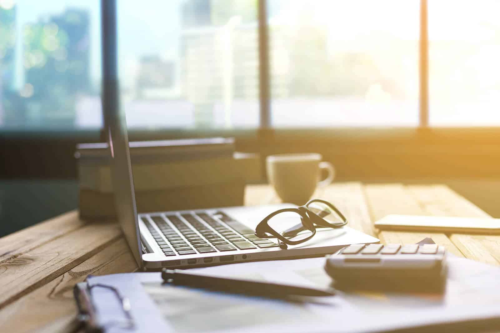 Laptop with eyeglasses, notebook, and coffee cup on a bright desk, reflecting professional SEO strategies for holistic health and wellbeing providers.