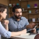 Man helping woman while sitting at a table pointing to a laptop. Discover how to find your ideal client and improve your private practice SEO today.