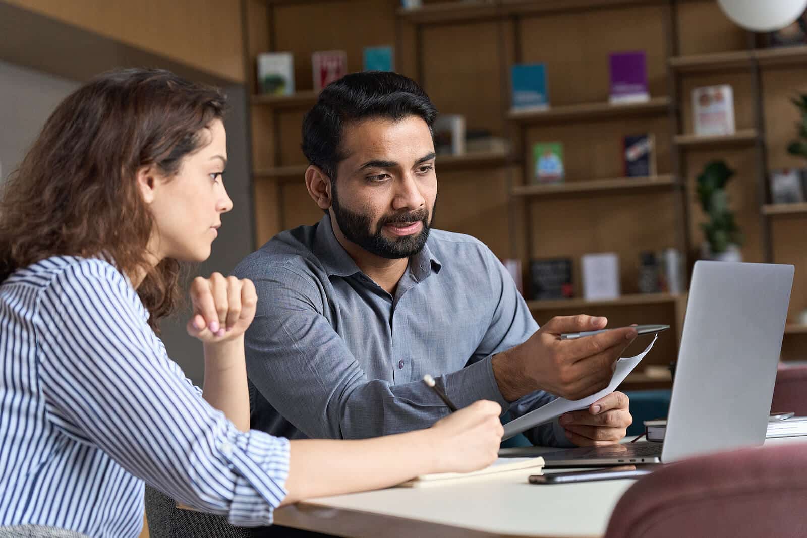 Man sitting at a desk next to a woman discussing information from a laptop. See your website begin to rise in rankings and find ideal clients you can support with Simplified SEO Consulting. Begin to work on your private practice SEO soon.