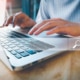 Hands typing on a laptop keyboard with a digital search bar overlay, representing SEO for holistic health and wellbeing.
