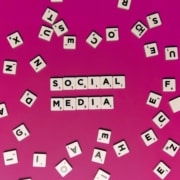 Social media spelled out on scrabble pieces on a magenta background. Our social media specialist can tie your social media strategy to your SEO strategy. Learn more by reading our blog here!