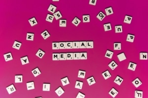 Social media spelled out on scrabble pieces on a magenta background. Our social media specialist can tie your social media strategy to your SEO strategy. Learn more by reading our blog here!