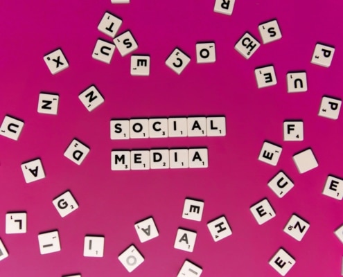 Social media spelled out on scrabble pieces on a magenta background. Our social media specialist can tie your social media strategy to your SEO strategy. Learn more by reading our blog here!