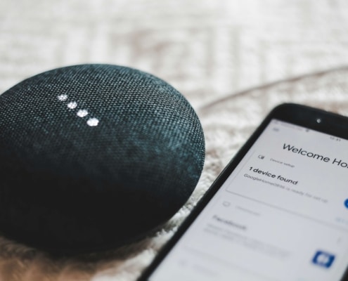 Google Home Mini smart speaker and smartphone on a textured surface, showcasing the impact of functional medicine SEO and local SEO doctors marketing in leveraging AI technology for better online visibility.