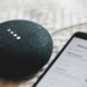 Google Home Mini smart speaker and smartphone on a textured surface, showcasing the impact of functional medicine SEO and local SEO doctors marketing in leveraging AI technology for better online visibility.