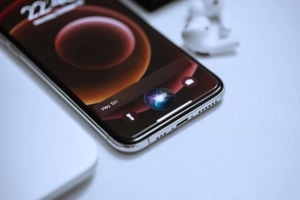 Person holding a smartphone with Siri activated, illustrating the role of AI in voice search and the importance of SEO for functional medicine doctors and SEO for holistic health and wellbeing.