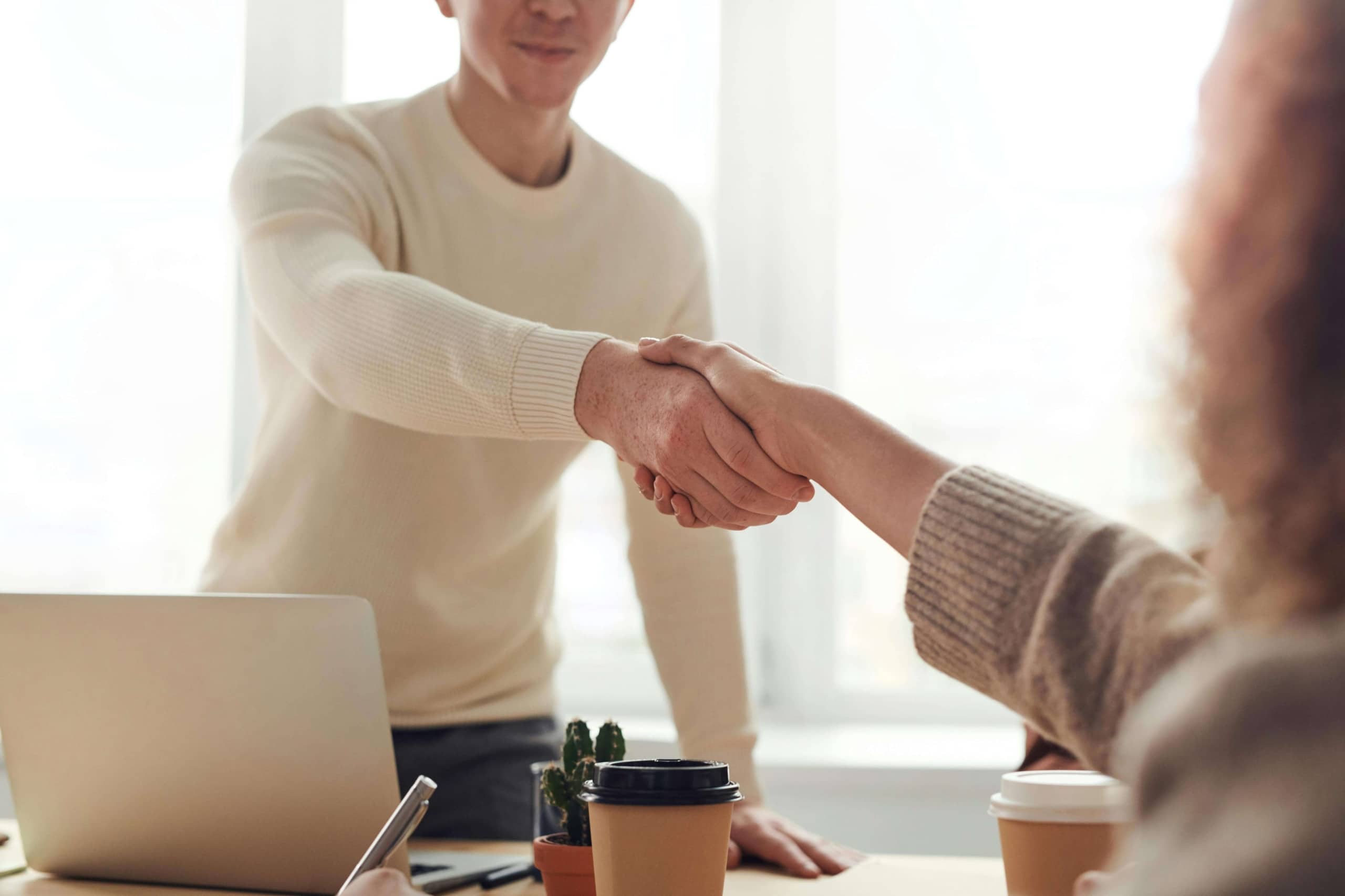 Two professionals shaking hands across a desk, representing the trust and connection built when holistic health providers use SEO for holistic health and wellbeing to show up online.