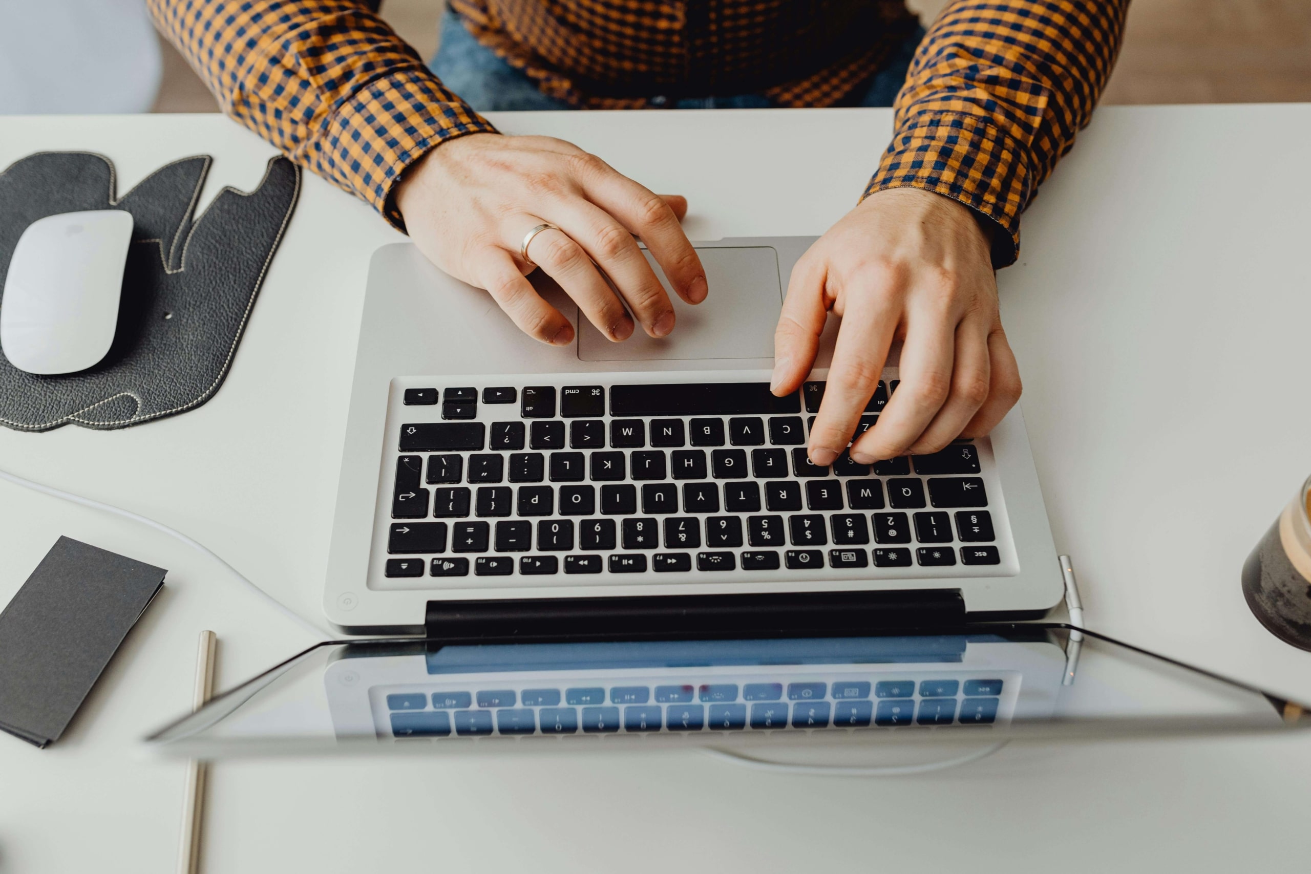 Close-up of hands typing on a laptop, illustrating the importance of creating optimized content through SEO for holistic health and wellbeing.