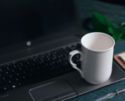 White coffee mug resting on a laptop, representing how holistic health providers use digital tools and SEO for holistic health and wellbeing to reach new clients in 2025.