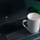 White coffee mug resting on a laptop, representing how holistic health providers use digital tools and SEO for holistic health and wellbeing to reach new clients in 2025.