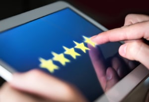 Close-up of a person giving a five-star review on a tablet, showcasing the impact of positive reputation management in local SEO for medical professionals and local SEO for therapists. Reviews like these are crucial for local SEO doctors marketing success. 