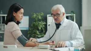 Doctor measuring a patient's blood pressure in a clinic, symbolizing the importance of SEO for functional medicine doctors and the role of SEO for functional medicine in connecting with patients online.