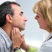 Woman doctor pressing against a man's throat during an appointment. With integrative medicine SEO you can ensure that the patients searching for your services find you first.