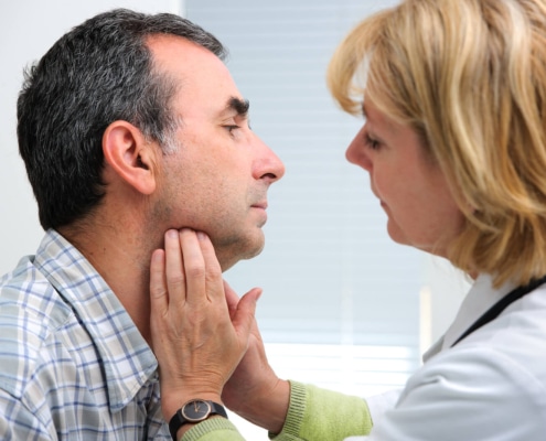 Woman doctor pressing against a man's throat during an appointment. With integrative medicine SEO you can ensure that the patients searching for your services find you first.