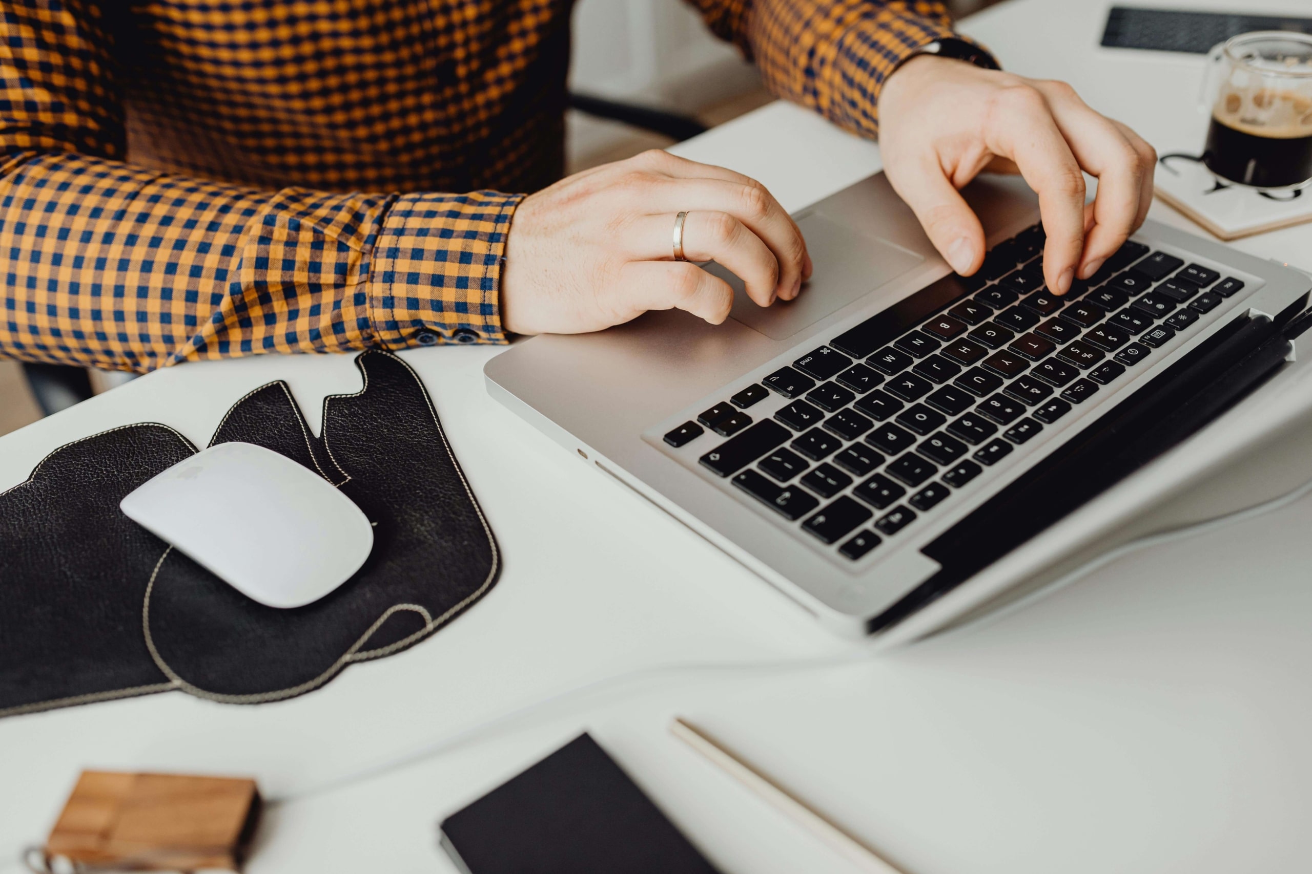 Person in a checkered shirt working on a laptop at a tidy desk, reflecting intentional effort and organization in applying holistic SEO for practitioners.