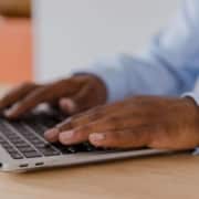 Close-up of hands typing on a laptop, symbolizing the behind-the-scenes work of optimizing websites through holistic SEO practices.