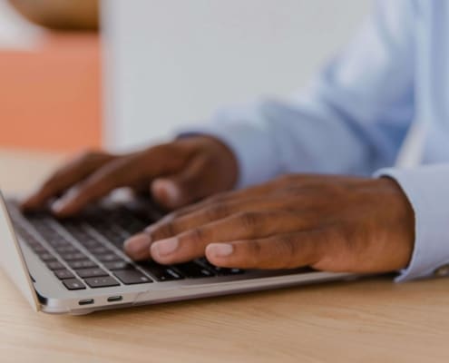 Close-up of hands typing on a laptop, symbolizing the behind-the-scenes work of optimizing websites through holistic SEO practices.
