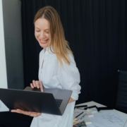 A holistic practitioner smiling while working on her laptop, representing how alternative healing SEO helps wellness providers grow their online presence.