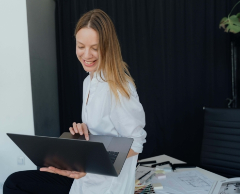 A holistic practitioner smiling while working on her laptop, representing how alternative healing SEO helps wellness providers grow their online presence.