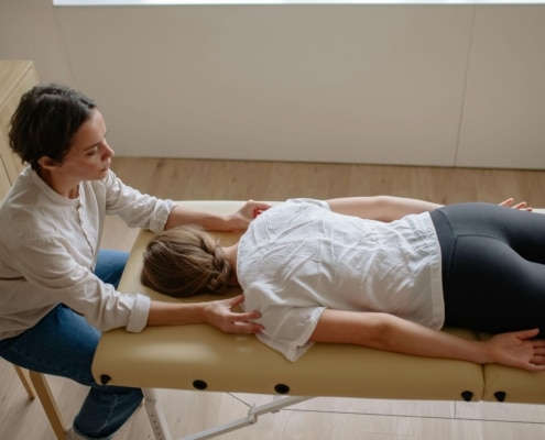 Therapist performing bodywork on a client lying on a massage table in a bright, minimalist room, illustrating the role of alternative healing SEO and wellness SEO in enhancing online visibility for holistic practitioners.