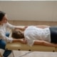Therapist performing bodywork on a client lying on a massage table in a bright, minimalist room, illustrating the role of alternative healing SEO and wellness SEO in enhancing online visibility for holistic practitioners.