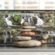 A stack of multicolored zen stones sits atop a laptop displaying a waterfall scene, blending technology with integrative medicine SEO. Are you considering how SEO consulting services could strengthen your clinic’s digital presence? Thoughtful strategy aligns care with visibility.