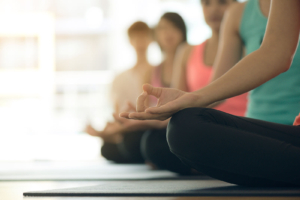 People sitting in a meditation class with a close-up of a hand in a relaxed mudra pose, reflecting holistic wellness and mental health support. The image symbolizes how seo for mental health, local seo for therapists, and private practice seo help mindfulness and wellness practitioners reach more clients, similar to local seo for medical professionals in traditional healthcare settings. 