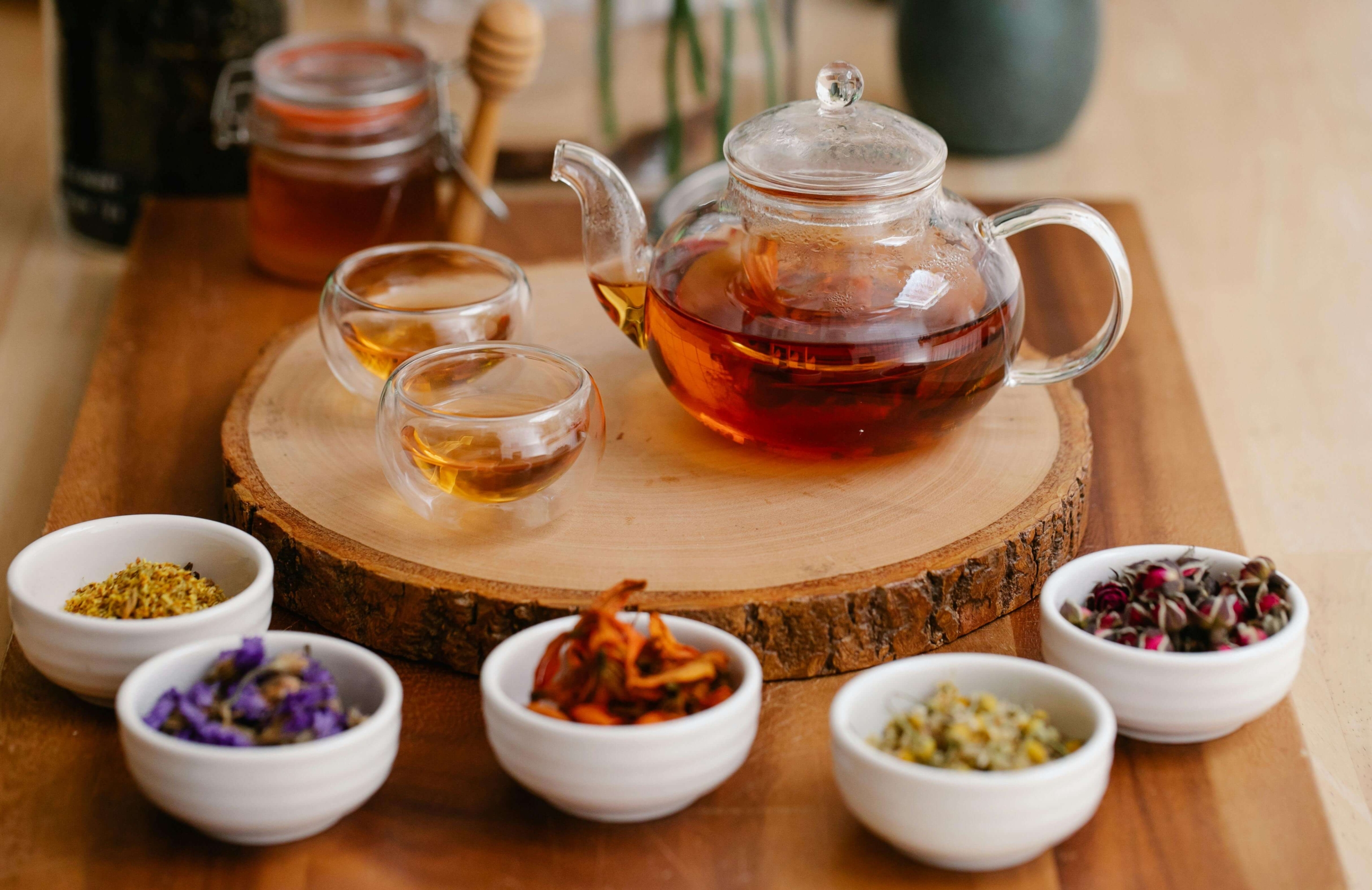A glass teapot and small cups of herbal tea sit neatly arranged on a wooden surface, creating a calm, natural wellness setting. The scene reflects how homeopathy practitioners can build trust through warmth, clarity, and consistency in their online presence. This approach aligns with effective SEO for homeopathy professionals.