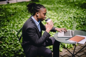 A professional man working on a laptop outdoors with a coffee cup in hand, symbolizing the role of health SEO and an SEO consulting firm in enhancing online visibility, featured in the blog 'Local SEO for Integrative Medicine: How to Dominate Your City’s Search Results'.