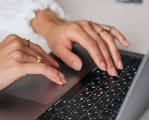 Close up of hands typing on a laptop keyboard while wearing gold rings. With integrative medicine SEO, intentional content creation becomes a powerful way to turn online searches into real patient inquiries.