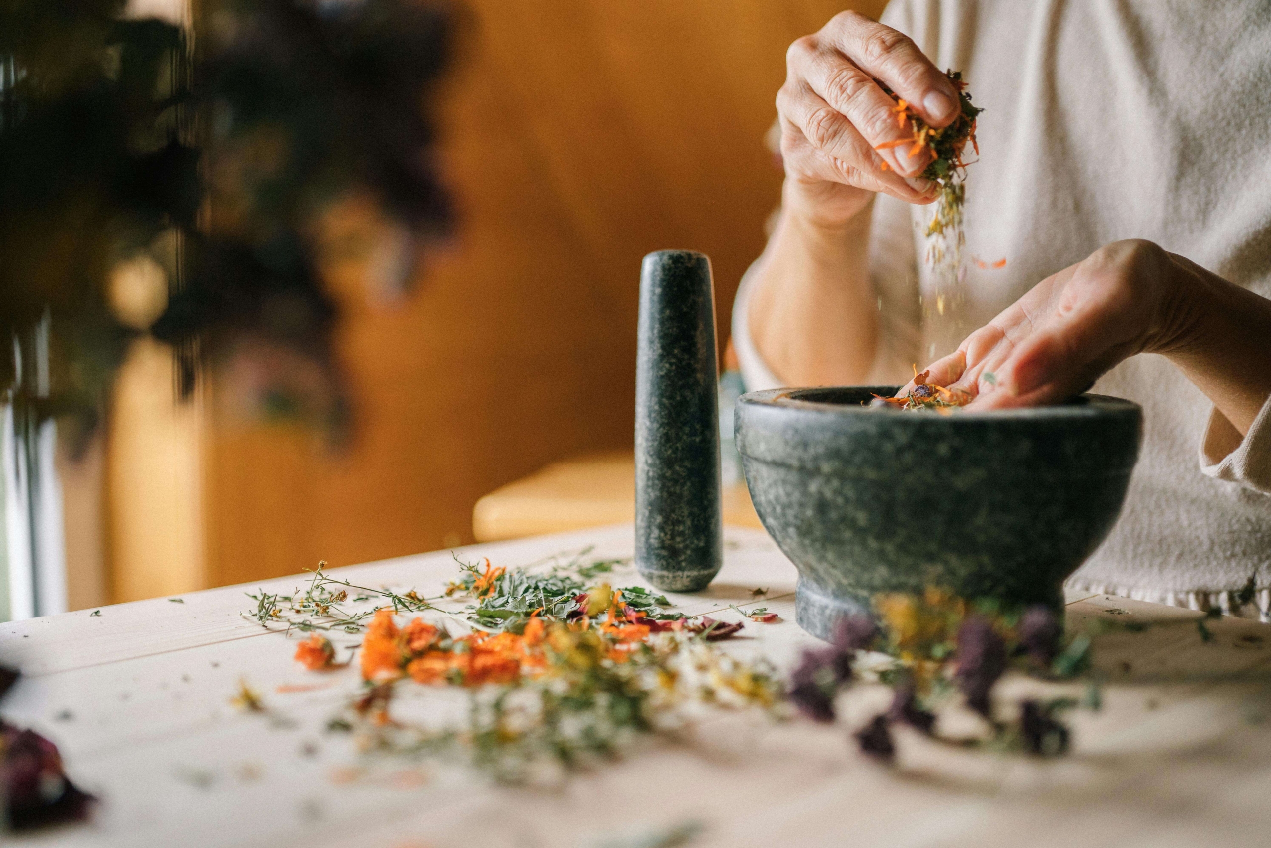 Hands gently mix dried herbs in a mortar and pestle, highlighting care, intention, and traditional healing practices. This moment represents how practitioners build trust by honoring process and expertise in their digital messaging. Thoughtful content strategy is a key element of homeopathy SEO.