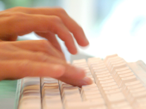 Close-up of hands typing on a white keyboard, representing a therapist or marketer writing content and choosing SEO keywords for mental health to improve SEO for mental health and overall search engine optimization for counselors. 