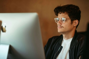 A male therapist with glasses looking at his computer curiously. Representing how SEO & social media marketing can feel overwhelming. Start working with an SEO specialist today to get more clarity on your marketing needs.