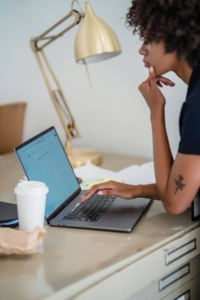 Woman thoughtfully reviewing content on a laptop at her desk, reflecting the careful editing process that shows why seo for medical practice websites matters and answers the question of is seo important for therapists using AI to create content.