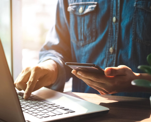 A person using a laptop and smartphone to search online, representing how SEO for therapists and private practice SEO work together to connect therapists with clients across multiple devices