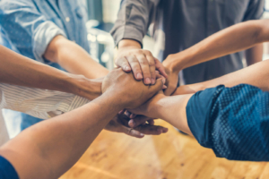 A group of people place their hands together in a show of teamwork and support. At Simplified SEO Consulting, our team takes a collaborative approach to SEO for therapists, keeping clients informed and supported every step of the way. 