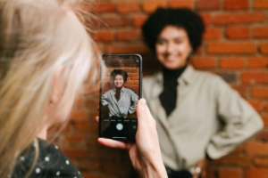 A friend taking a photo of a woman standing in front of a brick wall smiling. Content creation can feel overwhelming as a therapist. Learn how our social media management package can help you!