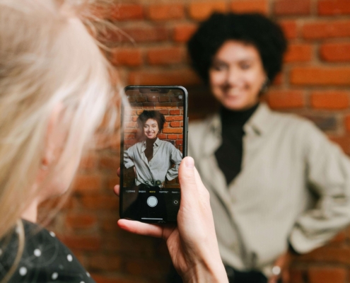 A friend taking a photo of a woman standing in front of a brick wall smiling. Content creation can feel overwhelming as a therapist. Learn how our social media management package can help you!