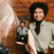 A friend taking a photo of a woman standing in front of a brick wall smiling. Content creation can feel overwhelming as a therapist. Learn how our social media management package can help you!