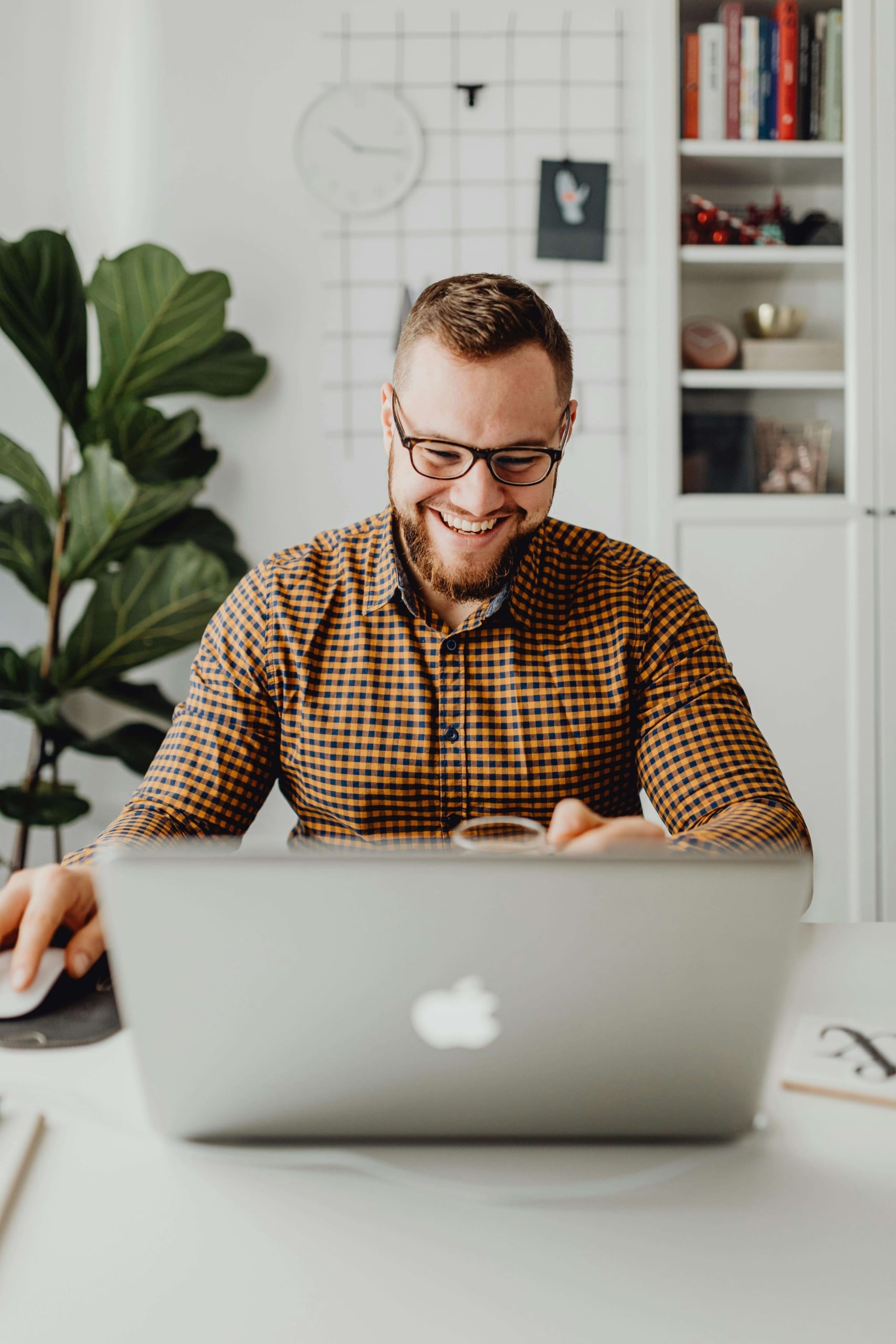 man with glasses | is seo important for therapists | seo for therapy practice | therapist seo | Arkansas | North Dakota | Idaho A smiling man with glasses and a beard sits at a white desk working on a laptop in a bright home office with a large plant and bookshelf behind him. When SEO for private practices is working the way it should, growing your therapy practice starts to feel a whole lot less stressful.