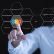 A person in a white shirt points at a digital display of hexagonal shapes showing SEO related terms including local SEO, artificial intelligence, EEAT, voice search, and mobile friendliness against a dark background. Understanding the full picture of SEO for therapy practice means knowing which fundamentals actually move the needle for your practice.