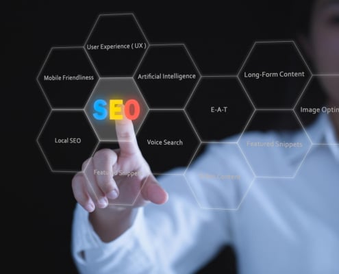 A person in a white shirt points at a digital display of hexagonal shapes showing SEO related terms including local SEO, artificial intelligence, EEAT, voice search, and mobile friendliness against a dark background. Understanding the full picture of SEO for therapy practice means knowing which fundamentals actually move the needle for your practice.
