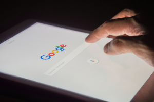 A person taps the Google search homepage on a tablet in a darkened room. SEO for therapists starts with understanding how search engines find and rank your website, making technical SEO services an essential foundation for any therapist trying to grow their practice online. 