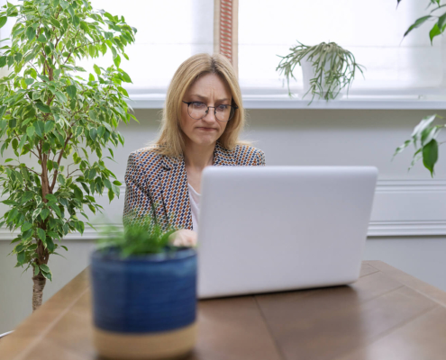 A therapist sits at her desk with a concerned expression while reviewing her website on a laptop. Understanding technical SEO services can feel overwhelming for helping professionals, but knowing what to look for is the first step toward better visibility online.