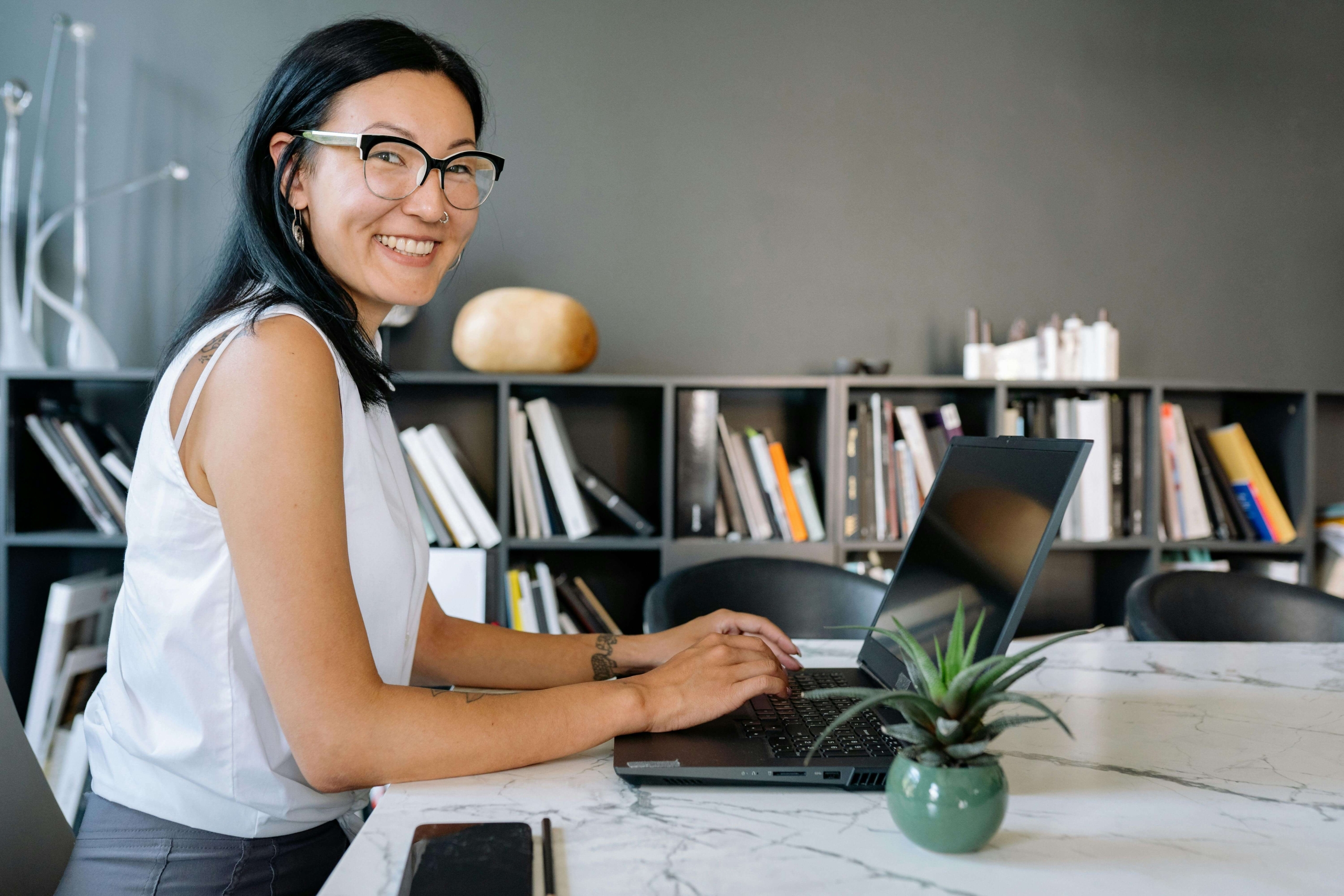 Therapist smiling while using a laptop, illustrating the integration of online tools and marketing strategies through SEO help for therapists.