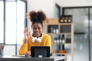 A woman smiles and waves during a video call on her tablet, wearing headphones around her neck. Connecting with an SEO specialist is an easy first step for anyone exploring SEO services for therapists or looking to improve the technical health of their practice website. 