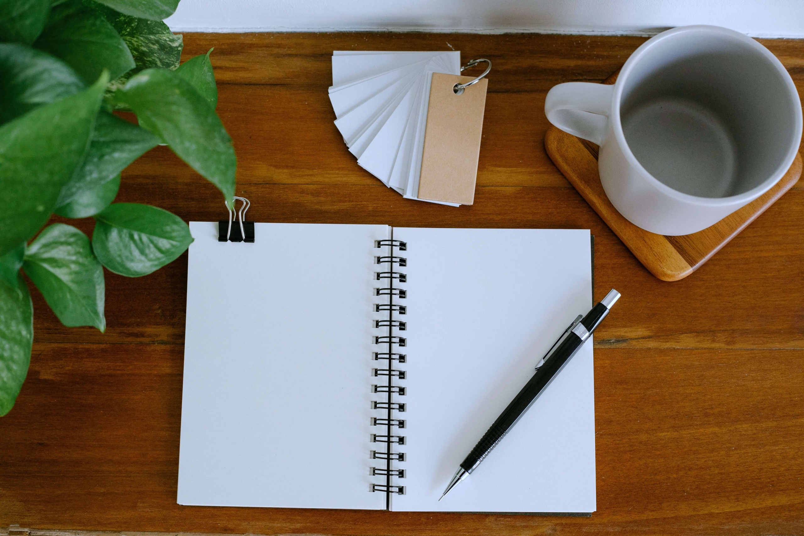 An open notebook, pen, and mug of coffee sit ready on a wooden desk. Does AI blogging still need a thoughtful human touch? SEO services for therapists start with real understanding, not just automated content.